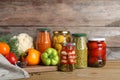 Glass jars with pickled vegetables on table against brown background Royalty Free Stock Photo