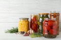 Glass jars with pickled vegetables on table against wooden background Royalty Free Stock Photo