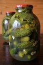 Glass jars with pickles, dill and garlic in glass jar on wooden table