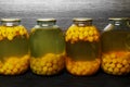 Glass jars with preserved cherry plum on wooden background