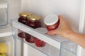 Glass Jars with raspberry and apple Jam on shelf in fridge. Female hand with a jar of red homemade jam. Fermented healthy foods Royalty Free Stock Photo