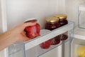 Glass Jars with raspberry and apple Jam on shelf in fridge. Female hand with a jar of red homemade jam. Fermented healthy Royalty Free Stock Photo