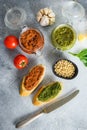 Glass jars with red and green pesto and cooking italian recipe ingredients Parmesan cheese, basil leaves, pine nuts, olive oil, Royalty Free Stock Photo