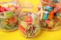 Glass jars of tasty colorful jelly candies on yellow background, closeup Royalty Free Stock Photo