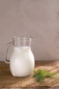 Glass jug with Ayran drink and a sprig of dill on a wooden background.