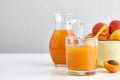 Glass and jug of fresh apricot juice on white table Royalty Free Stock Photo