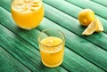 Glass and jug of fresh lemon juice on color wooden table Royalty Free Stock Photo