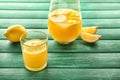 Glass and jug of fresh lemon juice on color wooden table Royalty Free Stock Photo