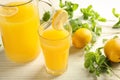 Glass and jug of fresh lemon juice on light wooden table Royalty Free Stock Photo