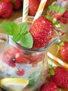 Glass jug is full of ice cubes, berries, lemon and mint