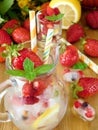 Glass jug full of ice cubes, berries, lemon and mint