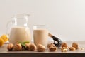 Glass and jug full of walnuts vegetable milk isolated background