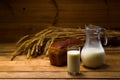 Glass jug with milk, mug with milk, a loaf of rye bread, ears