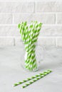 Glass jug with striped green drinking straws brick wall background Royalty Free Stock Photo