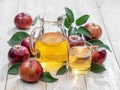 Glass of juice and carafe of fresh apple juice and organic apples on wooden table Royalty Free Stock Photo