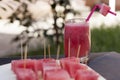 Glass of juice and cubic slices of watermelon on the cutting board. at outdoors in the garden. Picnic at outdoors.