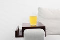 Glass of juice on sofa with wooden armrest table indoors. Interior element Royalty Free Stock Photo