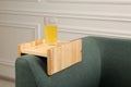 Glass of juice on sofa with wooden armrest table in room. Interior element Royalty Free Stock Photo