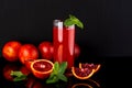 Glass of juice with a some pieces of sicilian orange on a black background. Sicilian orange drink.