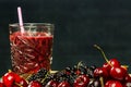 a glass of juice with a straw on a bamboo wooden board with cherries with stems Royalty Free Stock Photo