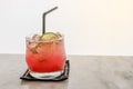 Glass of juicy punch with ice cube decorated with piece of lemon and straw on white background