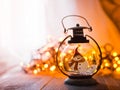 Glass lantern with burning candles Christmas presents and a glowing garland on a wooden table. Royalty Free Stock Photo
