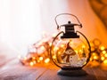 Glass lantern with burning candles Christmas presents and a glowing garland on a wooden table.