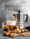 Glass of latte coffee on rustic wooden board, cantucci biscuits and steel Italian Moka pot, grey background Royalty Free Stock Photo