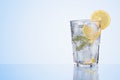 Glass of lemon drink with fresh lemons, mint and ice cubes on blue Royalty Free Stock Photo