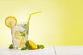 Glass of lemon drink with fresh lemons, mint and ice cubes on table on yellow background copy space Royalty Free Stock Photo