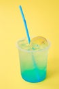 A glass with lemonade blue Lagoon with lemon, cold refreshing drink or beverage with ice on yellow Royalty Free Stock Photo