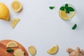 Glass with lemonade and ingredients for cooking. Ginger, lemon, mint on white surface. Wooden tray. Top view. Copy space Royalty Free Stock Photo