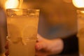 A glass with lemonade, lemon wedges, ice cubes. Summer cold refreshing drink in the hand of a man on the table in cafe Royalty Free Stock Photo