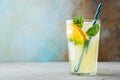 Glass with lemonade or mojito cocktail with lemon and mint, cold refreshing drink or beverage with ice on rustic blue background. Royalty Free Stock Photo