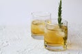 Drink in a glass with ice and a sprig of rosemary on a white background