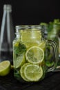 A glass of lemonade with sliced lime and lemon in a mug on a black background. Royalty Free Stock Photo