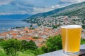 Glass of light beer against view from above on Senj town, Croatia. View from Nehaj Fortress, fort on the hill, Velebit, Croatia Royalty Free Stock Photo