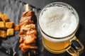 Glass of light beer with foam, pieces of smoked fish on a skewer, wheat crackers