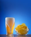 Glass of light beer with foam smudges and wavy chips