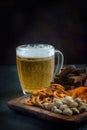 A glass of light beer and snacks on a dark background Royalty Free Stock Photo