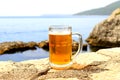 Glass of light beer near sea. Misted mug, pint of cold beer stands against background of blurred sea landscape in cafe, restaurant Royalty Free Stock Photo