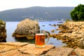 Glass of light beer near sea. Misted mug, pint of cold beer stands against background of blurred sea and mountain landscape in Royalty Free Stock Photo