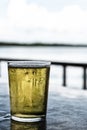 Glass of light beer Pilsner stands on the table of a summer cafe on a blurred background of the river Royalty Free Stock Photo