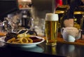 The glass of light beer and a plate of snacks on the bar Royalty Free Stock Photo