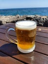 Glass of cold beer with sea view background.