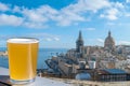 Glass of light beer with view of Valletta old town and harbor in Valletta, Malta