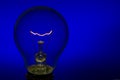 Glass light bulb with burning filament upright with blue background Royalty Free Stock Photo