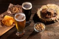 A glass of light and dark beer with various snacks to beer on a brown background. Royalty Free Stock Photo