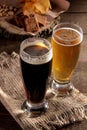 A glass of light and a glass of dark beer and snacks in the background on a brown table Royalty Free Stock Photo