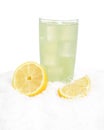Glass of lime juice with ice cubes,lemons halves on snow on white Royalty Free Stock Photo